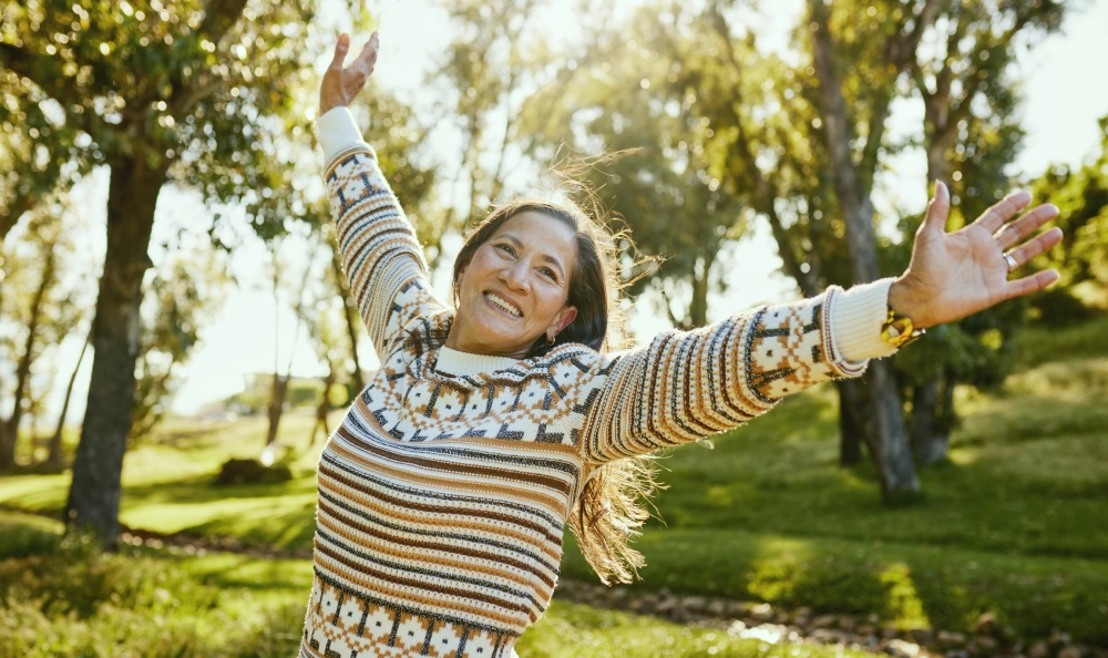 Woman in sweater smiling with arms out.